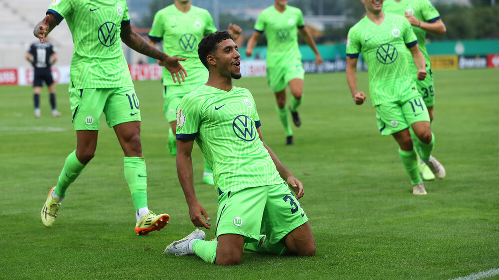 Omar Marmoush kniet vor Freude auf dem Rasen nach dem Tor in der Nachspielzeit im Du ell Jena vs. VfL Wolfsburg.