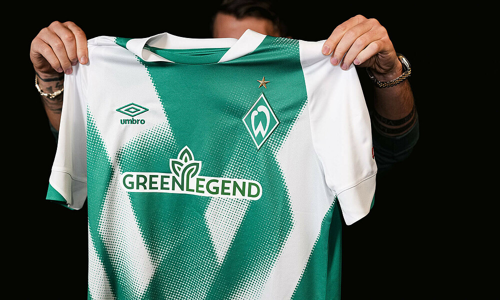 A Werder shirt with shirt sponsor Green Legend being held up