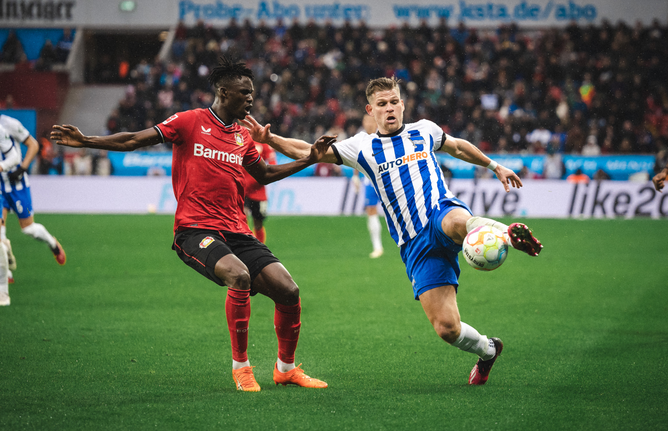 Florian Niederlechner competes for the ball with Leverkusen's Kossounou.