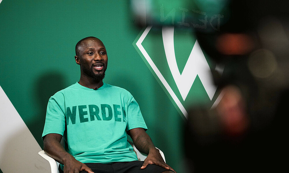 Naby Keïta in front of the camera in a Werder T-shirt.