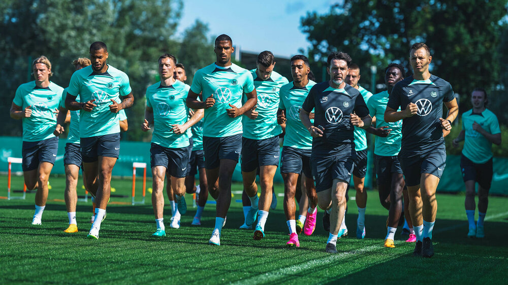 Die Spieler des VfL Wolfsburg laufen zum aufwärmen über den Trainingsplatz.