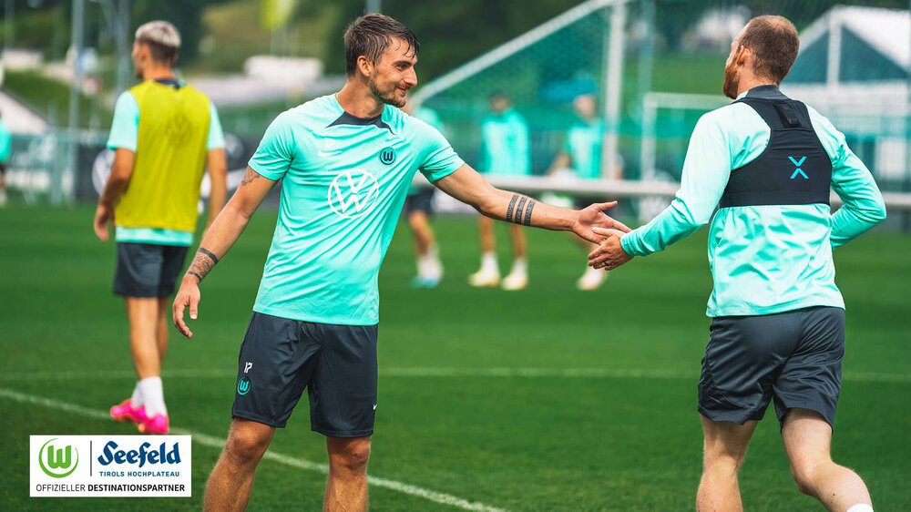 VfL Wolfsburg Spieler Philipp und Arnold klatschen sich am Spielfeldrand im Trainingslager ab.