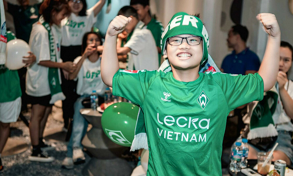 A child celebrating in Werder shirt and scarf.