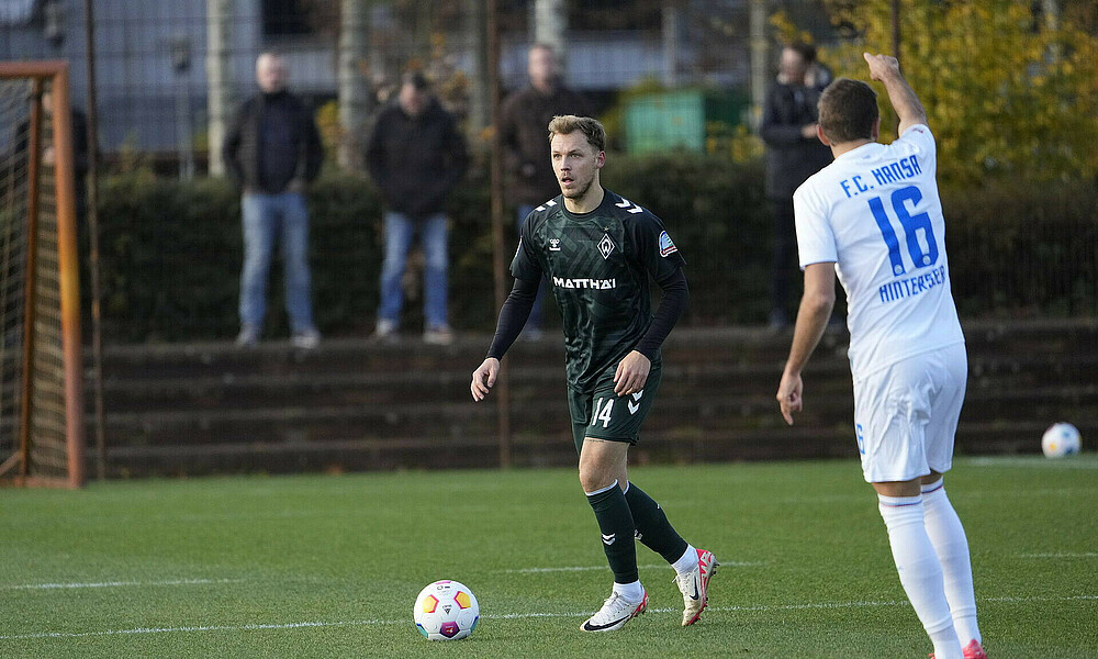 Senne Lynen with the ball at his feet and a Rostock player in the foreground