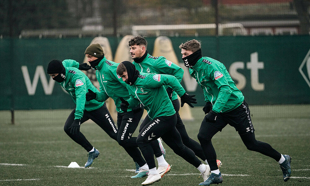 Werder players sprinting in a line during training.