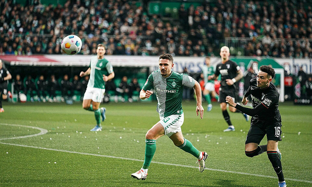 Milos Veljkovic in a race for the ball with Augsburg's Vargas.