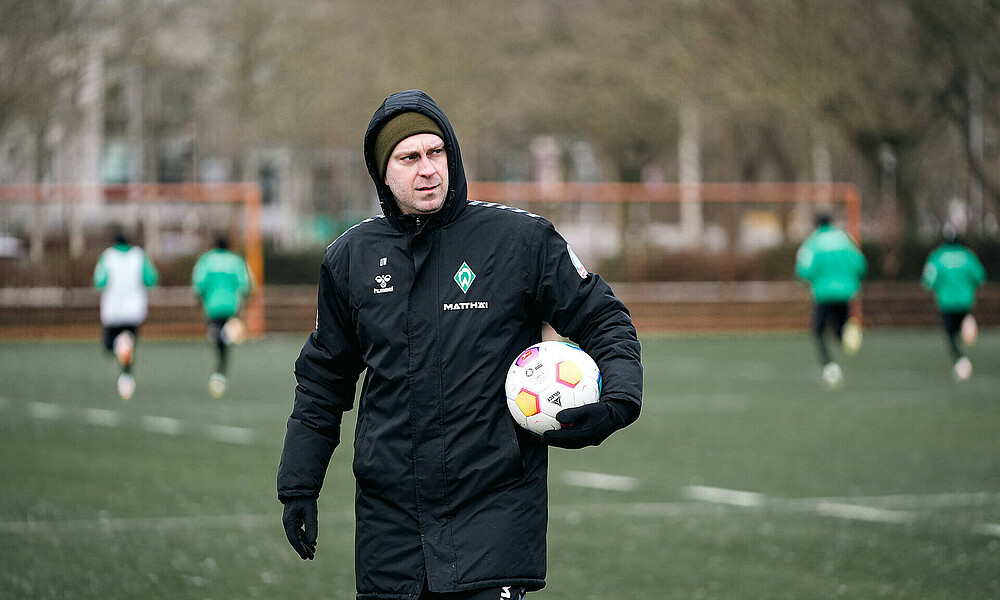 Ole Werner holding a football on the training pitch.