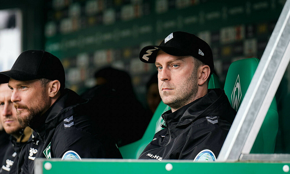 Ole Werner sitting on the bench and looking towards the pitch.