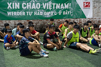 Children sitting in front of a banner in Vietnam.