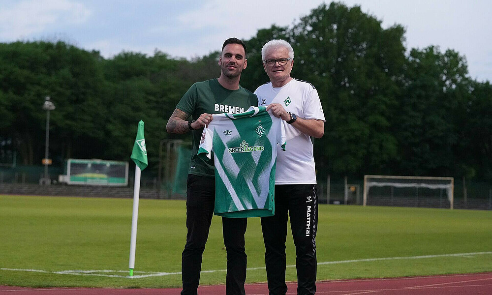 Rodrigo and kitman Stefan hold a jersey and smile.