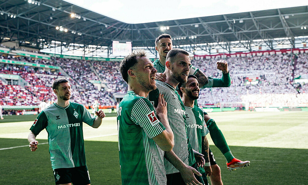 Werder players celebrate in front of the away fans in Augsburg.