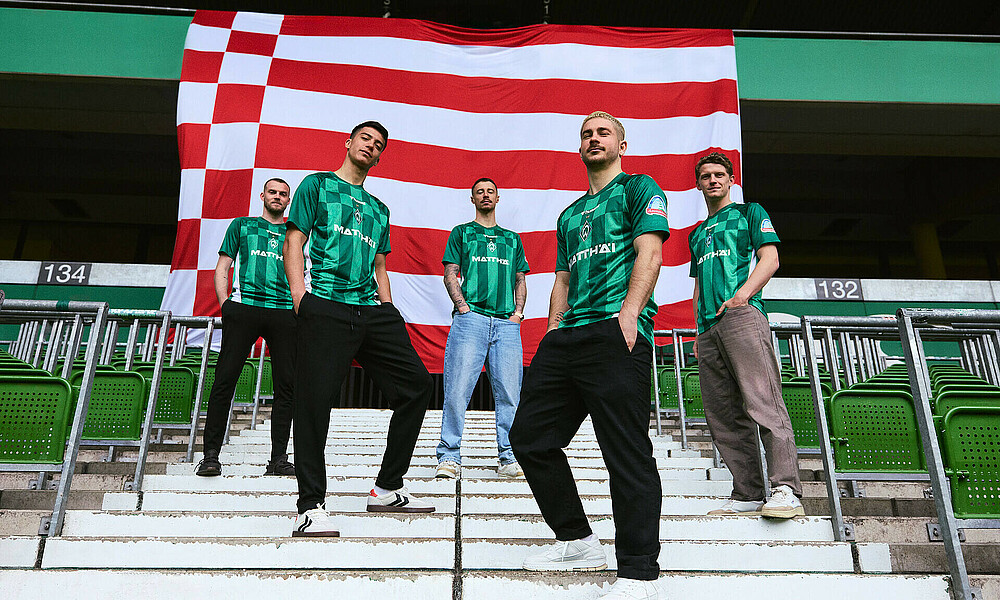 Marco Friedl, Romano Schmid, Julian Malatini and Jens Stage standing in front of the city of Bremen's flag.