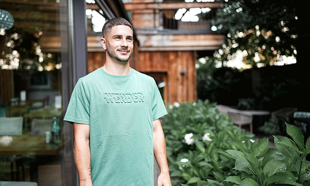 Romano Schmid in a green t-shirt with Werder lettering.