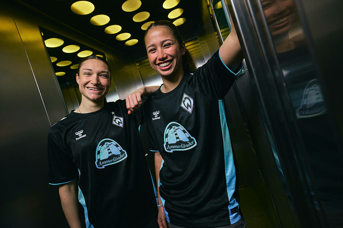 [Translate to Englisch:] Sophie Weidauer und Amira Dahl im Fahrstuhl im neuen Trikot.