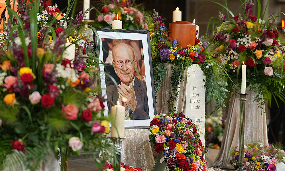 A portrait of Willi Lemke surrounded by flower bouquets.