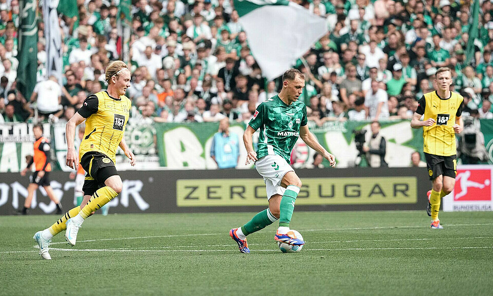 Senne Lynen dribbles with the ball with Julian Brandt running behind him.