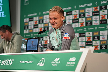 Amos Pieper sits on the Mixed Zone podium and smiles.