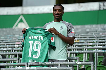 Derrick Köhn stands holding his number 19 shirt during his presentation