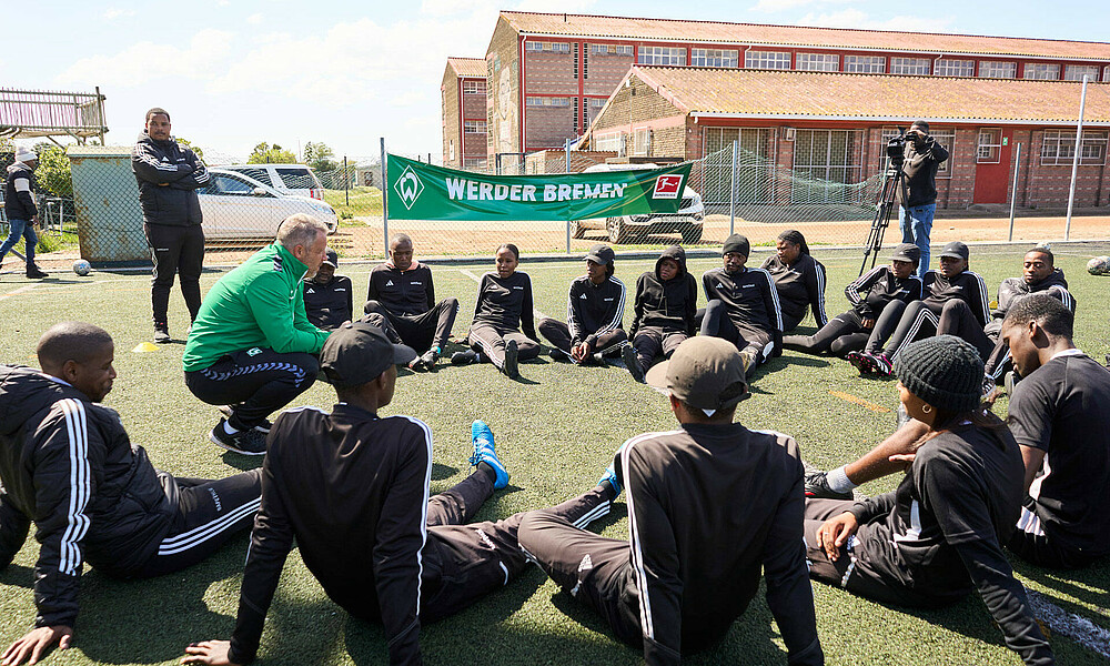 A group of people sit and listen to a coach