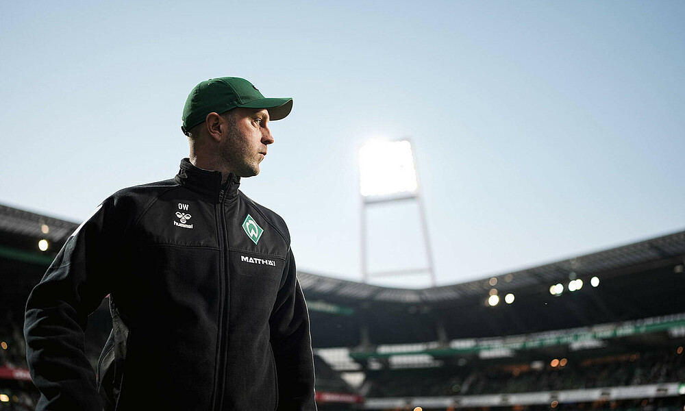 Ole Werner looks at the pitch with floodlights on in the background.