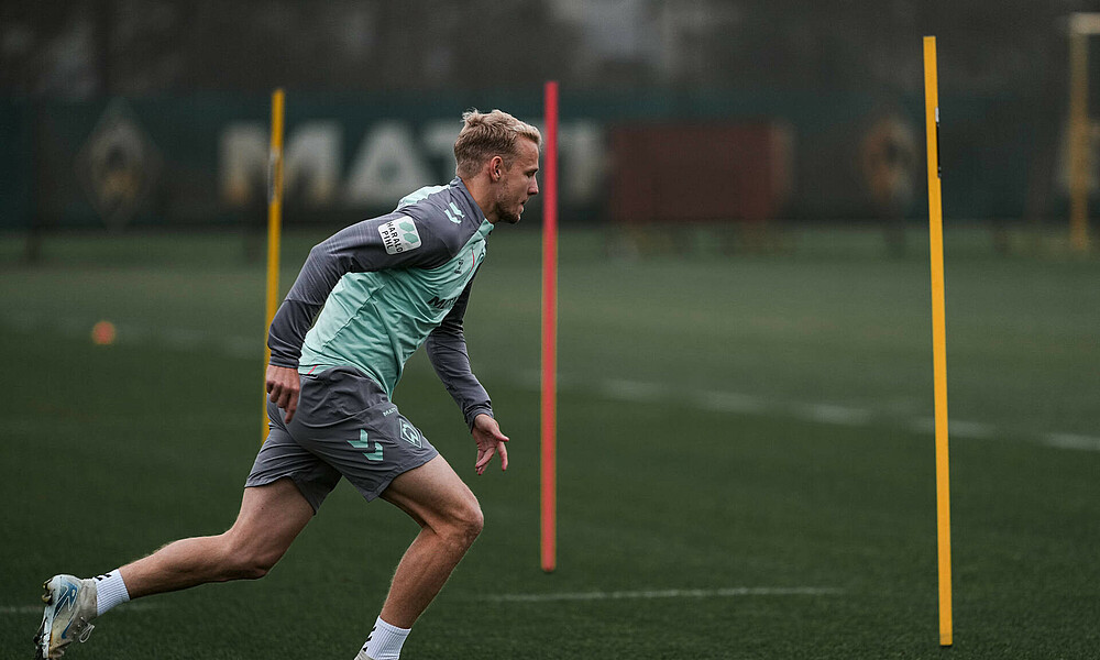 Marco Grüll running on the training pitch wearing a Werder training kit