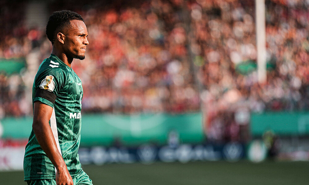 Felix Agu wearing Werder's green home shirt with the DFB-Pokal logo on the sleeve.